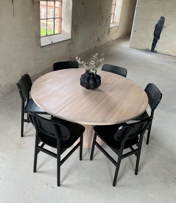 Circle dining table 150 with extension leaf. Whitewashed oak with 8 Rita 2.0 chairs in black An inviting & tasteful round dining table in Scandinavian design, made of solid oak, which makes the table feel genuine and authentic. The round solid dining table with extension leaves is really flexible and invites to large gatherings. Solid oak is used in the manufacture of high-quality furniture because of its durability and natural beauty. Solid oak top, solid oak & plywood columns, whitewashed oiled finish. Additional plate 50cm Pillar diameter 65cm. Height 74 cm. Oak is a living material with natural movements. Over time, influenced by light & humidity, shade & maturity can change